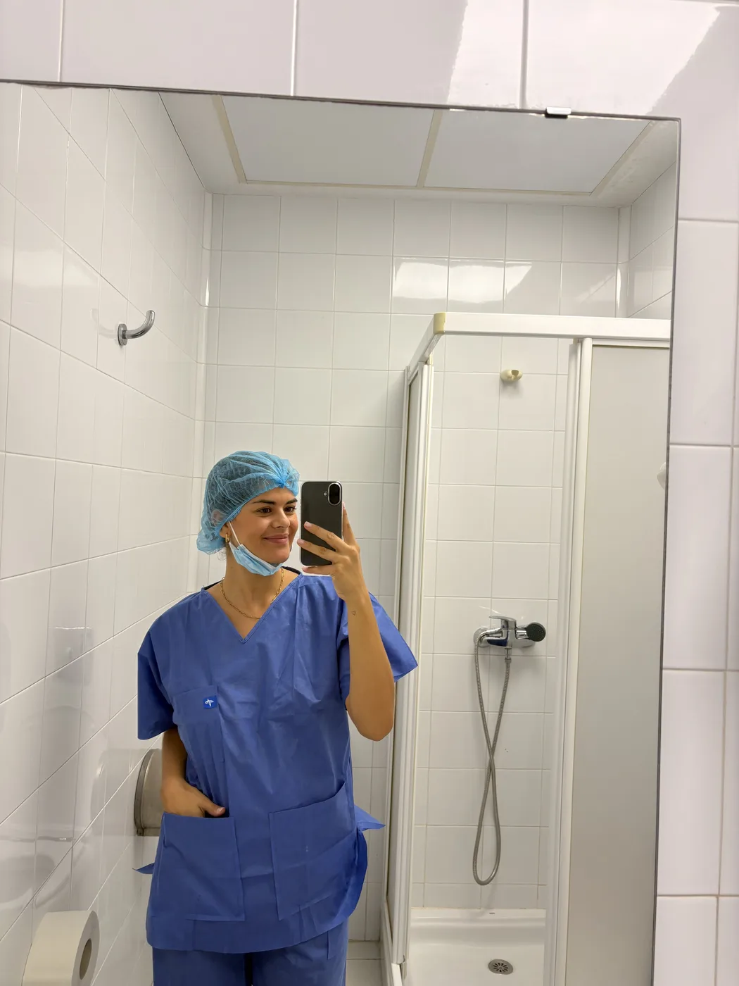 Daniela sonriendo en un selfie de espejo, con pijama quirúrgico azul